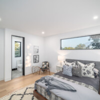 Bedroom with large rectangualr window above bed, view of the bathroom